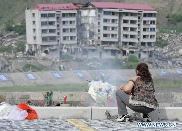 A woman burns joss paper to commemorate their beloved families lost in the 2008 Wenchuan earthquake in front of a destroyed building in Beichuan, southwest China's Sichuan Province, May 12, 2011. 