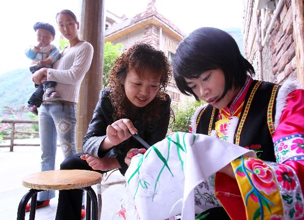 Jia Dehua (C) of Qiang ethnic group instructs a resident on embroidery skills in Enda Village, southwest China's Sichuan Province, May 10, 2011. 