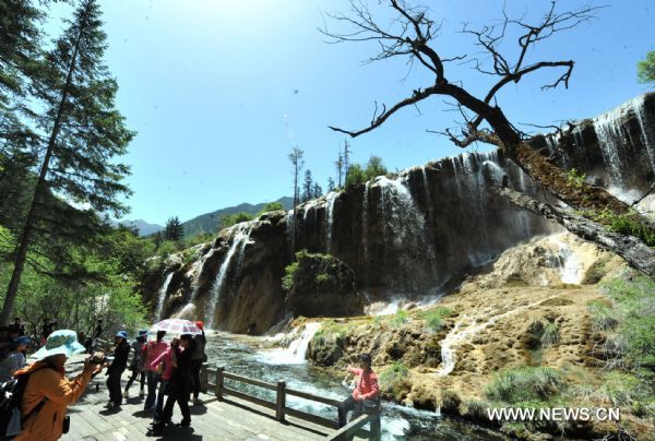 Tourists pose for photos in front of a fall in the Jiuzhaigou scenery spot in southwest China's Sichuan Province, on May 18, 2011. After three years' remedy and recovery, Jiuzhaigou, a renowned resort once had been badly affected by a deadly earthquake, is booming in its tourism business, with the daily reception number reaching nearly 10,000 in May. (Xinhua/Chen Haining) (hdt) 