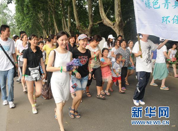 A participant ties a green ribbon on a tree in Nanjing, Jiangsu Province to promote a low-carbon lifestyle on July 10, 2011. 