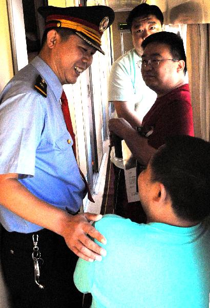 Gu Xingfu (L), a conductor, talks with passengers in the T27 train from Beijing, capital of China, to Lhasa, southwest China's Tibet Autunomous Region, July 18, 2011.