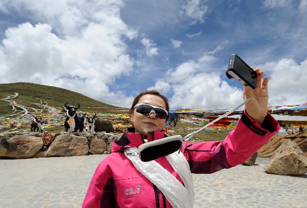 A woman takes photos of herself on the Milha Mountain in Nyingchi of southwest China's Tibet Autonomous Region, July 2, 2011.