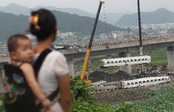Cranes lift derailed train carriages at the site where the high-speed train crash occurred in Wenzhou, east China's Zhejiang Province, July 24, 2011.