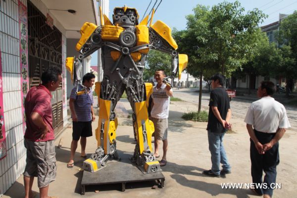 Citizens watch a 'transformer Bumblebee' made by a welder in Zhijiang City, central China's Hubei Province, July 25, 2011. As the film 'Transformers 3' was on show in China recently, welder Xiong Wei in Zhijiang made a Bumblebee model out of waste car and motorcycle parts in 12 days. Xiong planned to sell the 2.7-meter-high 'transformer' to a company in Shenzhen for exhibition. (Xinhua/Liu Weidong) (llp) 