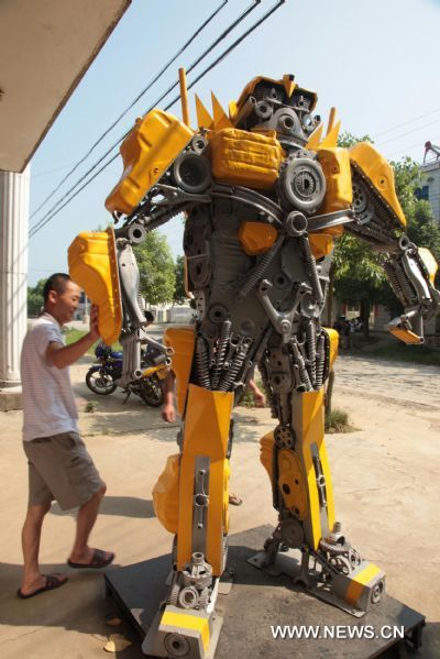 A citizen watches a 'transformer Bumblebee' made by a welder in Zhijiang City, central China's Hubei Province, July 25, 2011. As the film 'Transformers 3' was on show in China recently, welder Xiong Wei in Zhijiang made a Bumblebee model out of waste car and motorcycle parts in 12 days. Xiong planned to sell the 2.7-meter-high 'transformer' to a company in Shenzhen for exhibition. (Xinhua/Liu Weidong) (llp) 