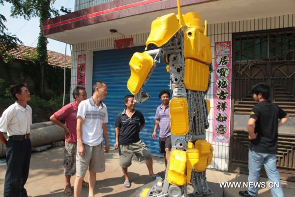 Citizens watch a 'transformer Bumblebee' made by a welder in Zhijiang City, central China's Hubei Province, July 25, 2011. As the film 'Transformers 3' was on show in China recently, welder Xiong Wei in Zhijiang made a Bumblebee model out of waste car and motorcycle parts in 12 days. Xiong planned to sell the 2.7-meter-high 'transformer' to a company in Shenzhen for exhibition. (Xinhua/Liu Weidong) (llp) 