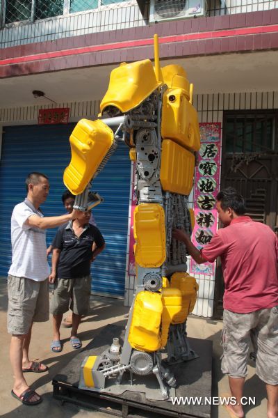 Citizens watch a 'transformer Bumblebee' made by a welder in Zhijiang City, central China's Hubei Province, July 25, 2011. As the film 'Transformers 3' was on show in China recently, welder Xiong Wei in Zhijiang made a Bumblebee model out of waste car and motorcycle parts in 12 days. Xiong planned to sell the 2.7-meter-high 'transformer' to a company in Shenzhen for exhibition. (Xinhua/Liu Weidong) (llp) 