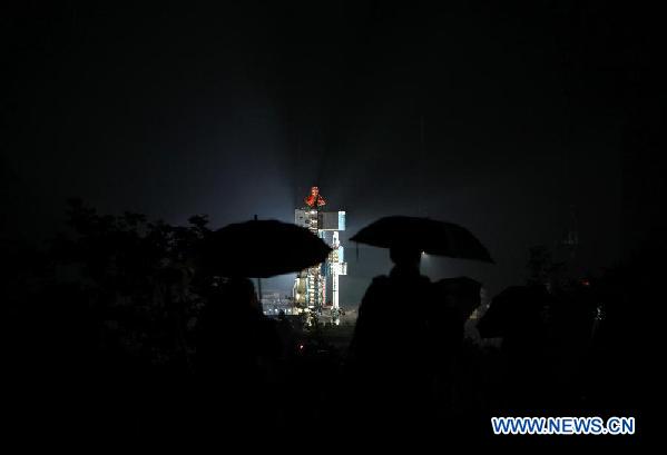 Journalists wait in rain for the launch of an orbiter at the Xichang Satellite Launch Center in southwest China's Sichuan Province, July 27, 2011.