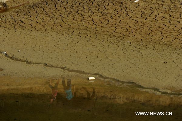 People are reflected upon the leftover water in a reservoir in Qianxi County, southwest China's Guizhou Province, July 28, 2011.