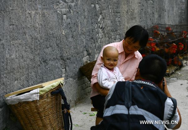 A baby smiles as a photographer shoots her in Zhouqu County of Gannan Tibetan Autonomous Prefecture, northwest China's Gansu Province, Aug. 2, 2011.