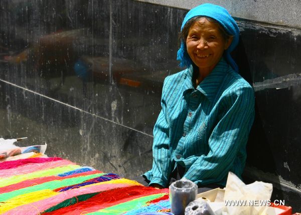 A vendor selling yarn simles at the camera in Zhouqu County of Gannan Tibetan Autonomous Prefecture, northwest China's Gansu Province, Aug. 2, 2011. 