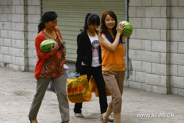 Women carry watermelons in Zhouqu County of Gannan Tibetan Autonomous Prefecture, northwest China's Gansu Province, Aug. 2, 2011. 