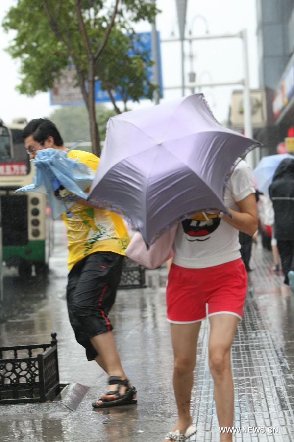 Citizens walk against wind as a fierce storm brought by Typhoon Muifa hits Yantai, a coastal city in east China&apos;s Shandong Province, Aug. 8, 2011.