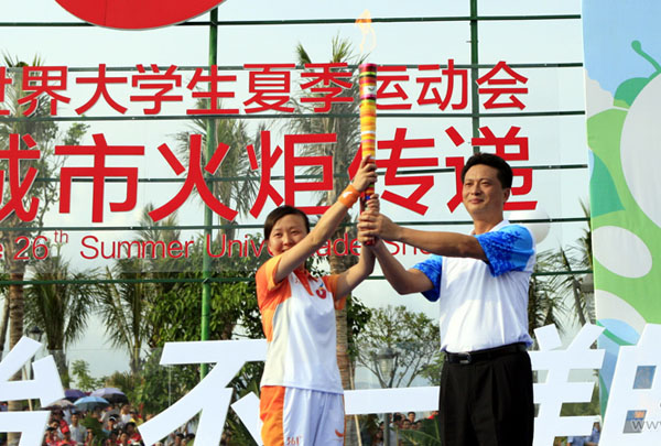 Zhang Wen, Vice mayor of Shenzhen, hands over the Universiade torch to Sun Ying, the No.1 torchbearer during the torch relay of the 26th Summer Universiade,in Shenzhen,China, August 7, 2011.