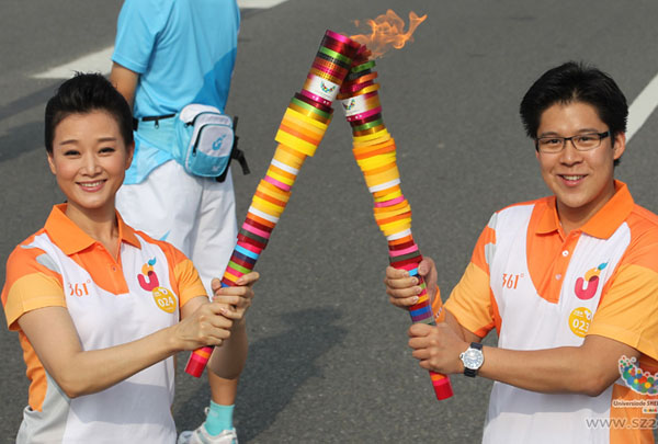 Famous singer Song Zuying, passes the Universiade flame to Huo Qigang,a famous Hongkong entrepreneur during the Torch Relay of the 26th Universiade,Shenzhen,China,Aug 7,2011.