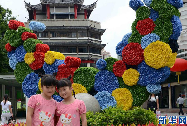 Twin sisters take a photo in front of the beautiful flowerbed in Shenzhen City, southeast China&apos;s Guangdong Province, Aug.10, 2011. 