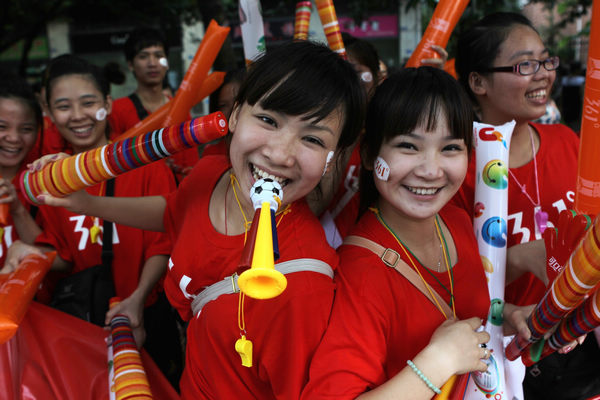 Shenzhen residents pose for pictures as they watch the torch relay for the 2011 Universiade on Thursday in the city's Longgang area. 