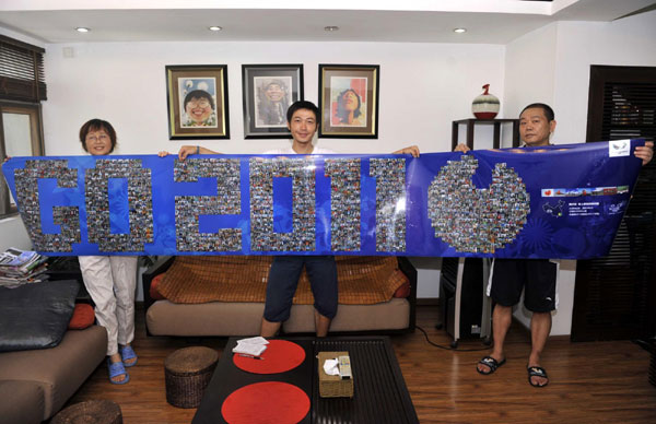 Zhou Ziqian and his parents show a collage of photos of people posing with UU, the mascot for the Shenzhen Summer Universiade, in Shenzhen, Guangdong Province, on August 14, 2011. 