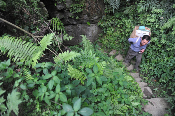 Wu carries water on a hilly road in Qinglong County, Guizhou Provincee, on Aug 17, 2011. 