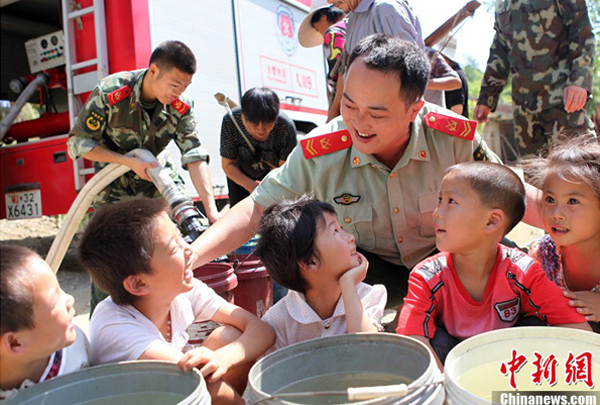 Villagers receive fresh water from the local fire brigade in Yongchuan District of Chongqing Municipality Aug. 17, 2011. 