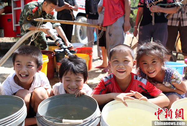 Villagers receive fresh water from the local fire brigade in Yongchuan District of Chongqing Municipality Aug. 17, 2011. 