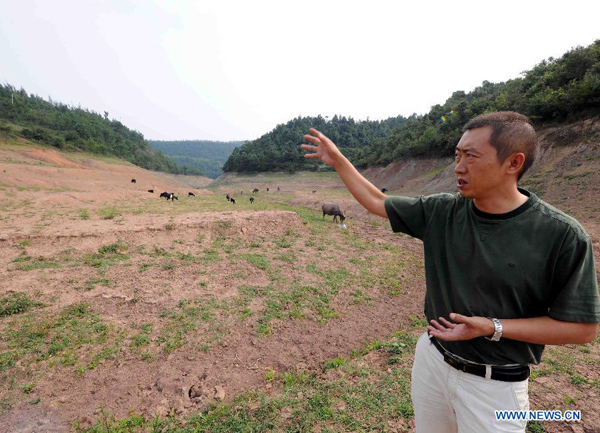 Lin Peihua, an official of the township government, shows the dried-up reservoir at Wangjia Town of Malong County in Qujing City, southwest China's Yunnan Province, Aug. 25, 2011.