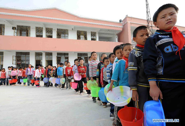 Students queue up for water delivered by a vehicle at Zhongtun Primary School of Wangjia Town in Malong County of Qujing City, southwest China's Yunnan Province, Aug. 25, 2011. 