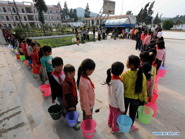 Students queue up for water delivered by a vehicle at Zhongtun Primary School of Wangjia Town in Malong County of Qujing City, southwest China's Yunnan Province, Aug. 25, 2011. 