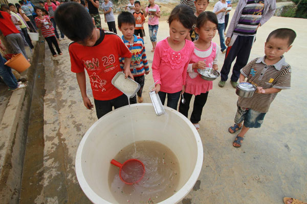 Students pour used water into a big bucket. The dirty water will be used to wash the toilets at Gengsha School in Fengshan County, south China&apos;s Guangxi Zhuang Autonomous Region, Sept 7, 2011. 