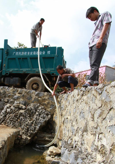 Workers pump water into a water wagon from a spring 15 kilometers away from Gengsha School in Fengshan County, south China&apos;s Guangxi Zhuang Autonomous Region, Sept 7, 2011.