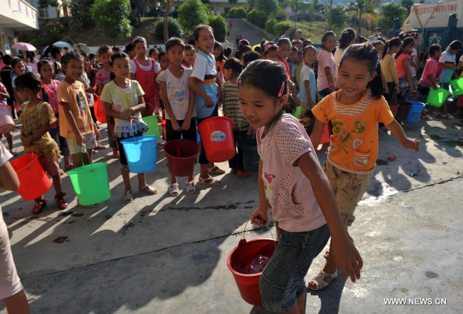 Students of Jiuzhou Township Elementary School get drinking water with barrels in Tianlin County, south China&apos;s Guangxi Zhuang Autonomous Region, Sept. 7, 2011.