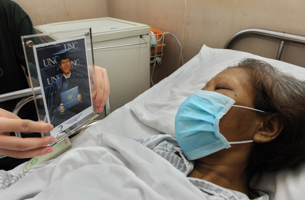 Chen Xumei, lying in sickbed, looks at a graduation photo of her son who donated 60 percent of his liver to her during organ transplant surgery at a hospital in Guangzhou, south China&apos;s Guangdong Province on Sep 10, 2011.