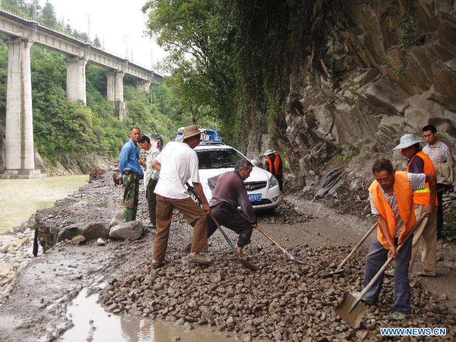 People try to clear up the road blocked by landslides in Qinghua Township of Wanyuan, southwest China&apos;s Sichuan Province, Sept. 14, 2011. 