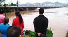 Residents look on rising waters in Quxian County, southwest China's Sichuan Province, Sept. 19, 2011.