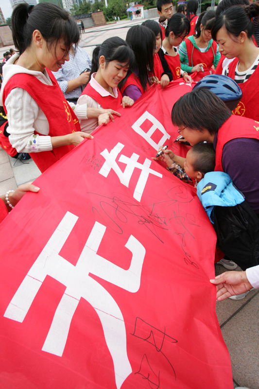 People sign their signatures on a banner to advocate World Car Free Day, September 22 in Weifang, Shandong Province.