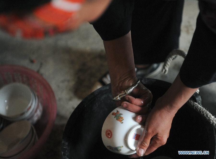 A villager washes dishes with damp hands at home at Guisa village in Zhenyuan County, southwest China&apos;s Guizhou Province, Sept. 23, 2011. 