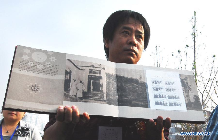 Li Chen, a professor of Luxun Academy of Fine Arts, who is also the designer of the commemorative stamps marking the centennial of 1911 (Xinhai) Revolution, shows the stamps in Wuhan, capital of central China&apos;s Hubei Province, Oct. 10, 2011.