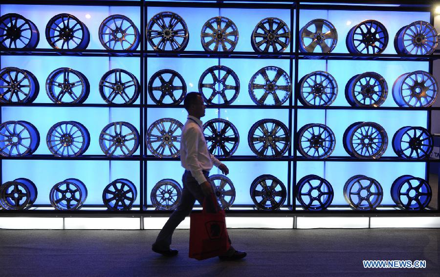 A visitor walks past wheel hubs on display during the 2011 China International New Energy Vehicles Industry Promotion Week in Beijing, capital of China, Oct. 13, 2011.