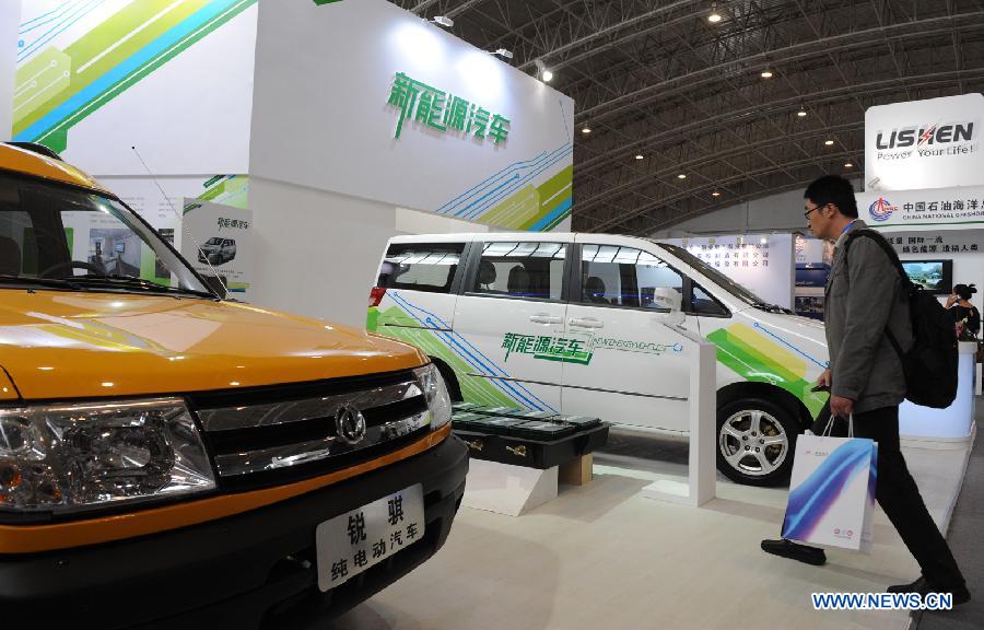 A visitor walks past battery-driven vehicles during the 2011 China International New Energy Vehicles Industry Promotion Week in Beijing, capital of China, Oct. 13, 2011. 