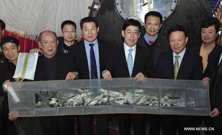 Guests from central-south China&apos;s Hunan Province hold a piece of local embroidery, retrieved from the re-entry capsule of China&apos;s unmanned spacecraft Shenzhou-8, in Beijing, capital of China, Nov. 21, 2011.