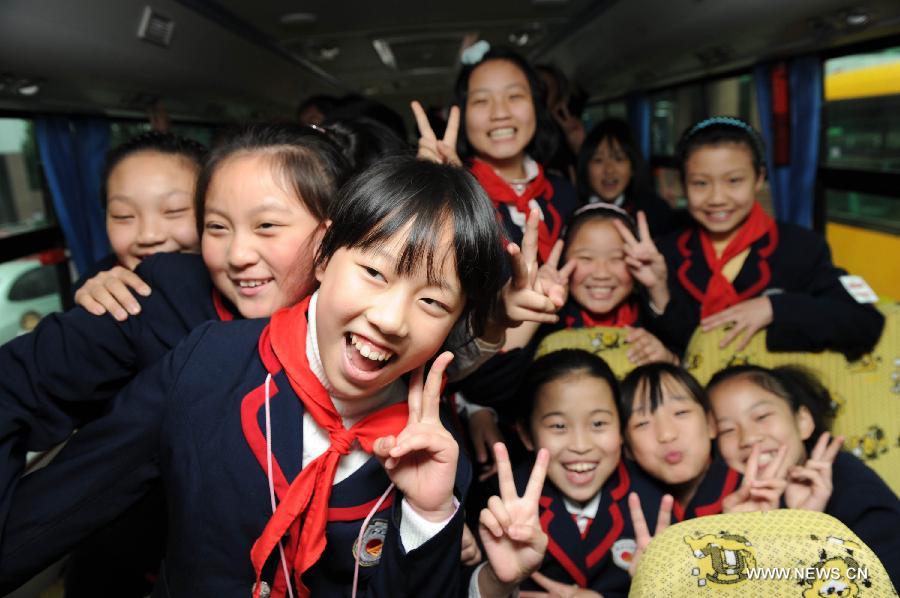 Children pose on a new school bus in Chongqing, southwest China, Nov. 22, 2011. The first school bus company of Chongqing was founded in Yubei District on Tuesday.