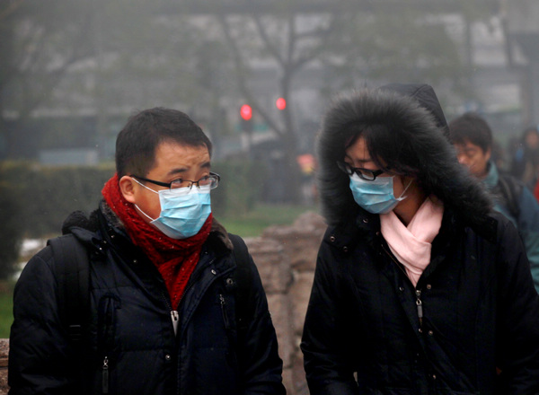 Two Beijing pedestrians wear masks as they walk on the street on Tuesday to protect them from the heavy smog. 