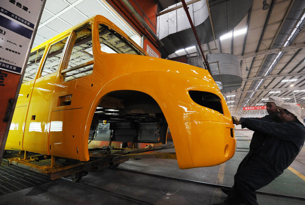 Two workers pull a bus body from a paint workshop in Hengtong Bus Co in Chongqing last month.