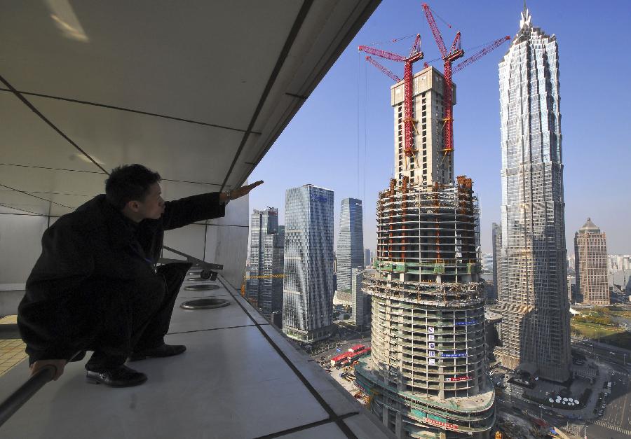 A man points to the Shanghai Tower (front) under construction alongside the Jin Mao Tower and Shanghai World Financial Center in Shanghai, east China, Jan. 17, 2012. 