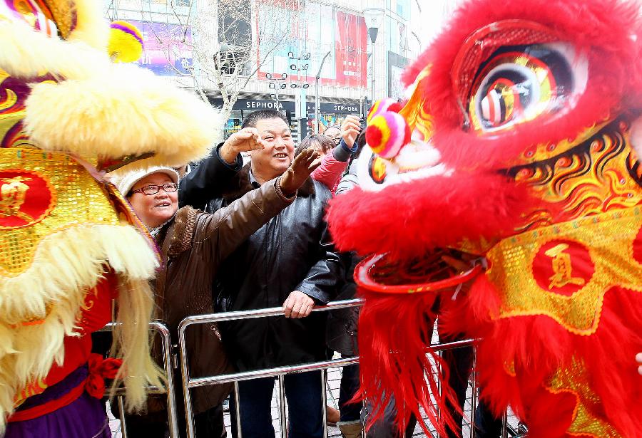 Tourists interact with dancing lions in Shanghai, east China, Jan. 30, 2012.