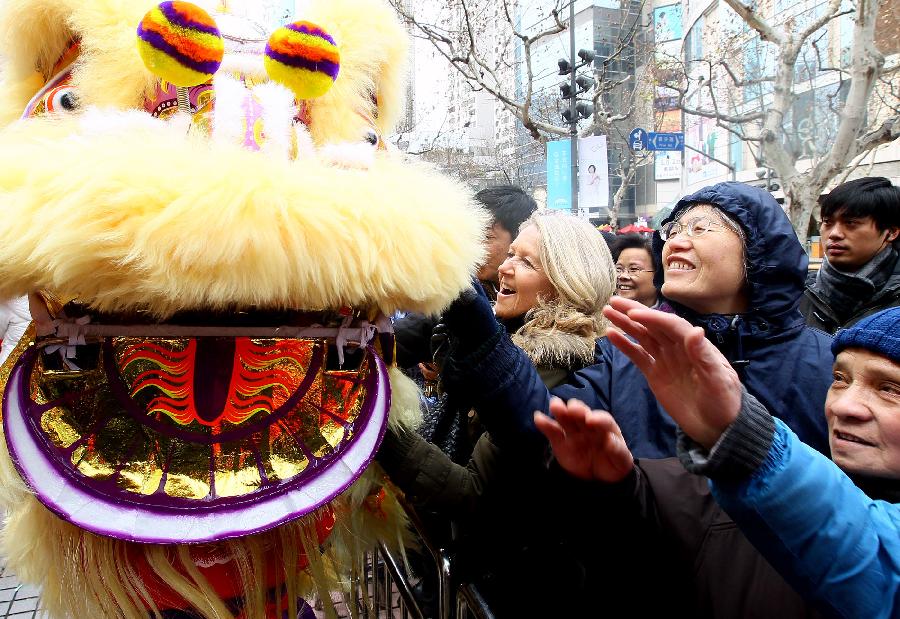 Tourists interact with a dancing lion in Shanghai, east China, Jan. 30, 2012.