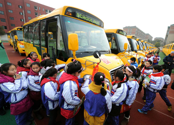 Students look at their new school buses at a primary school in Nanjing, capital of east China&apos;s Jiangsu Province, Feb 6, 2012.