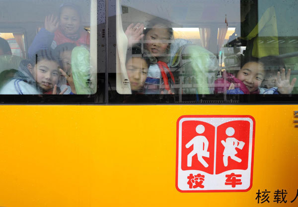 Students wave goodbye as they take a ride on their new school bus, Feb 6, 2012.