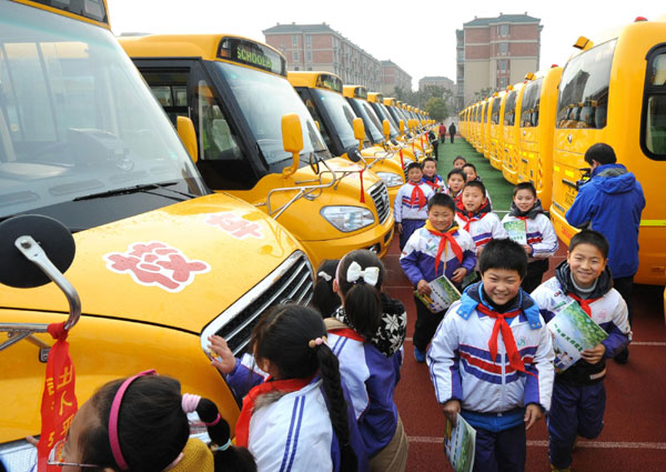 Students look at their new school buses at a primary school in Nanjing, capital of east China&apos;s Jiangsu Province, Feb 6, 2012. 