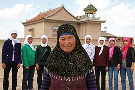 The eight Hui women standing in front of a mosque are clients of Yinongdai platforms. They set up a joint credit group as warrantors for each other. Yang Hui hua (M), the eldest, was elected group leader. Every month, they gather in Yang's home to meet, learn to read and farming technologies. Sometimes they sing songs and chat.